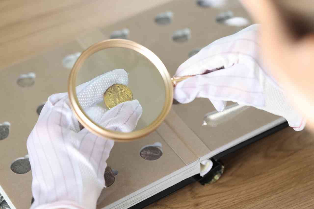 Especialista em numismática avaliando moeda com uma lupa