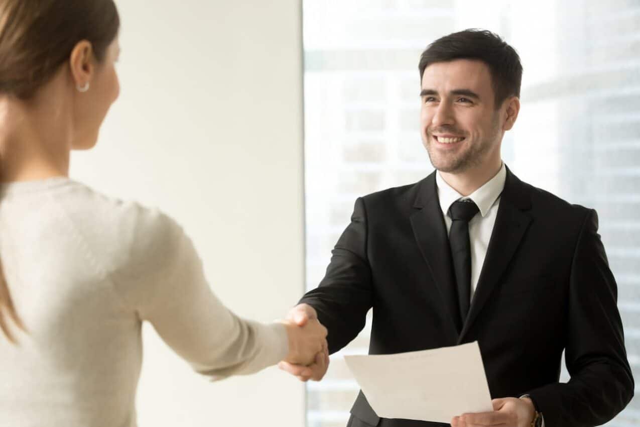 Recrutador apertando a mãe de jovem mulher, candidata a primeiro emprego