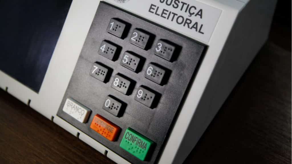 A imagem mostra uma urna de votação.