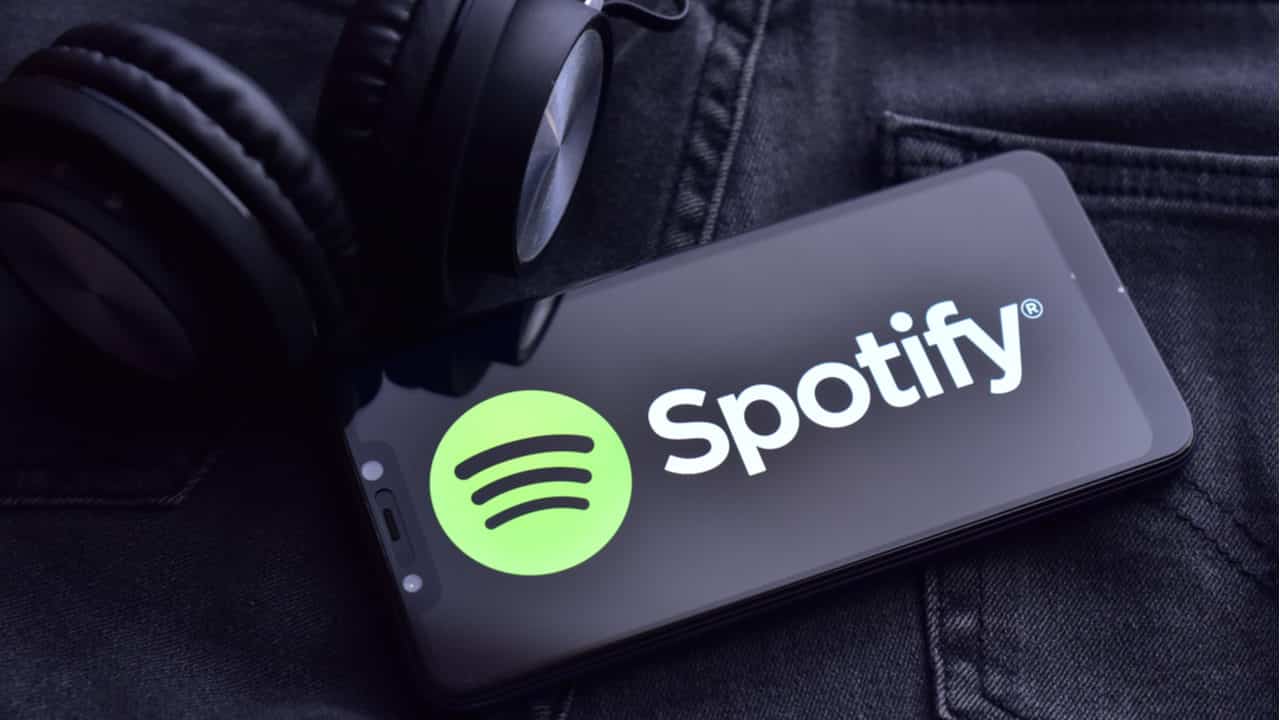 Celular com logo do Spotify e fones de ouvido