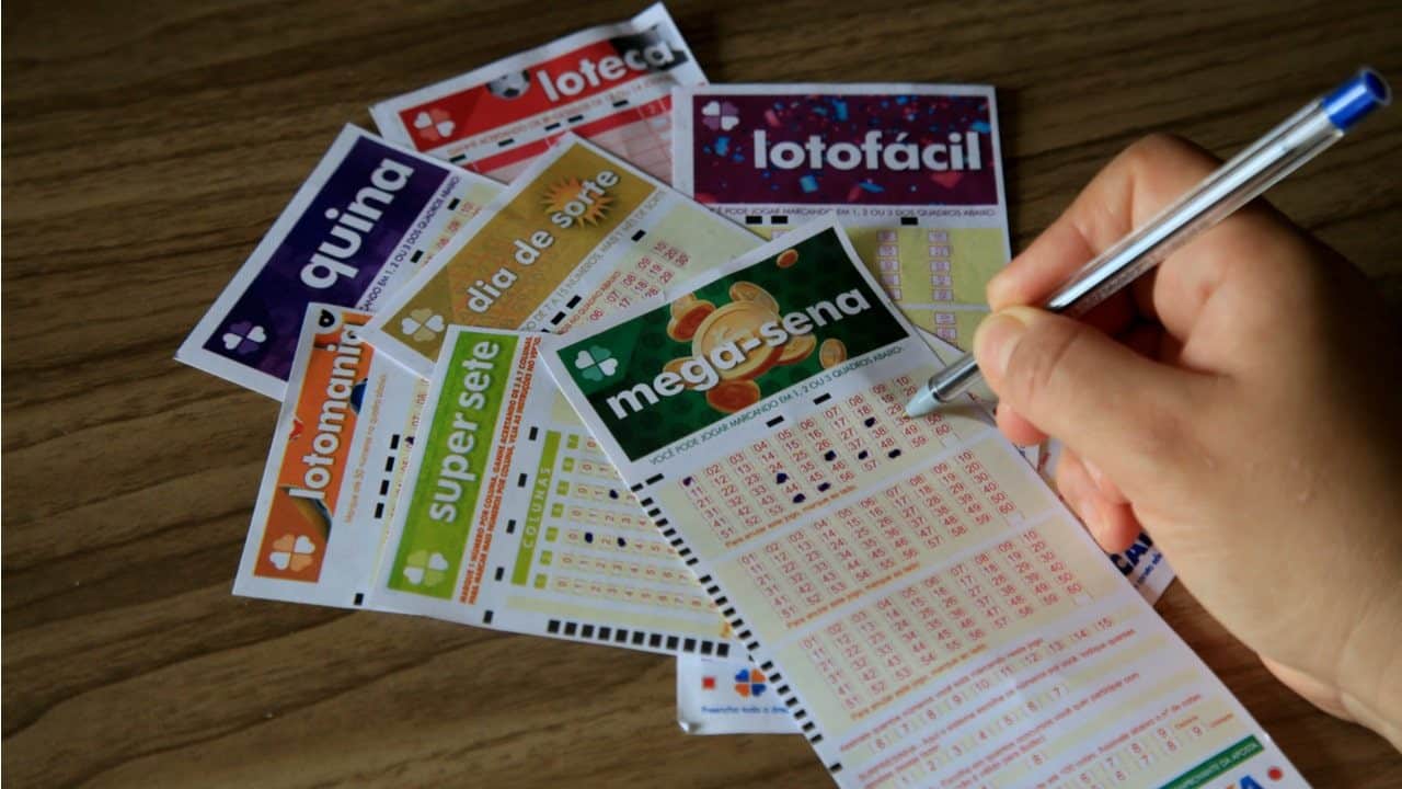 Mão segurando caneta pintando números da loteria.