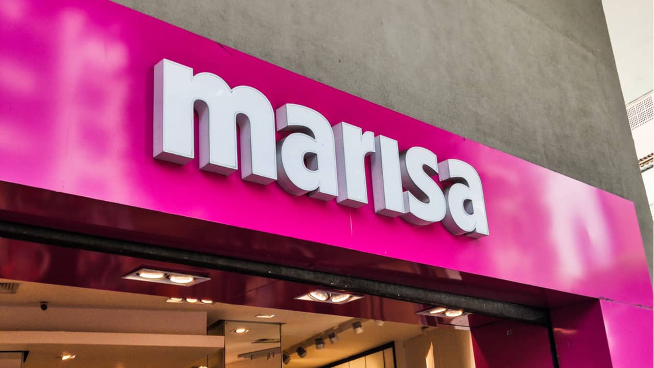 Imagem da fachada de uma loja Marisa com fundo rosa e letras brancas.