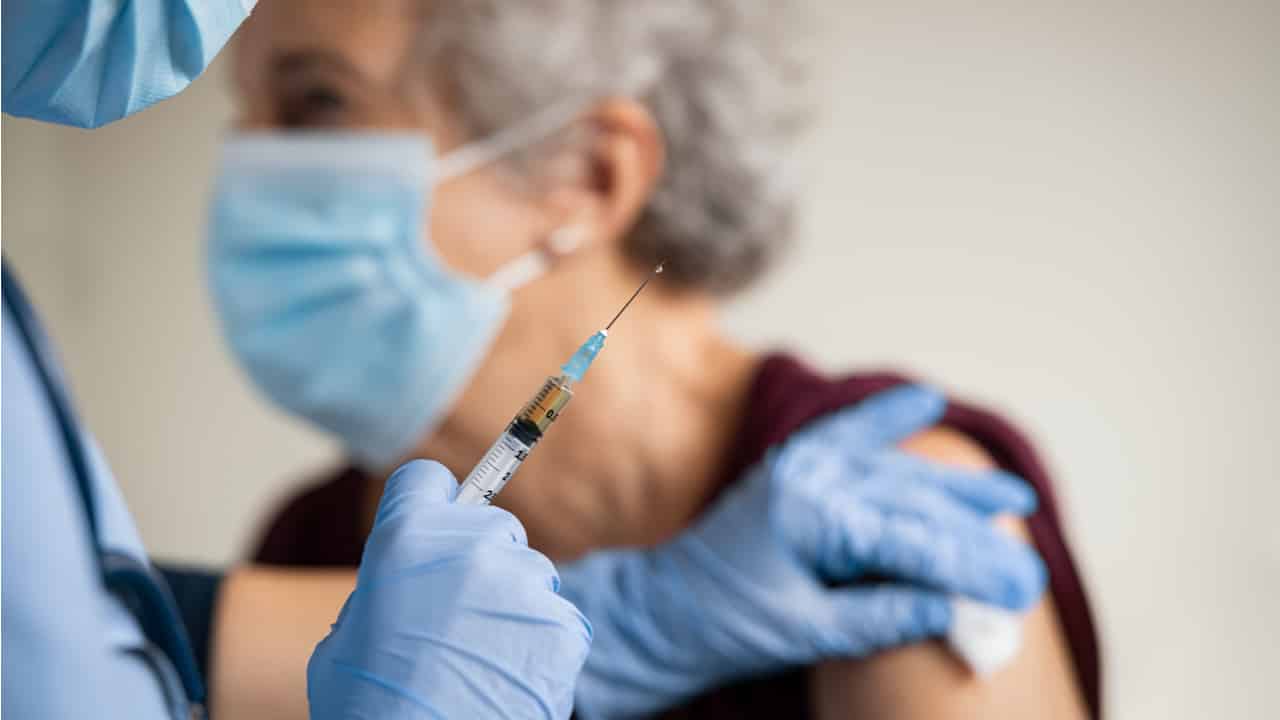 médico vacinando uma senhora no braço