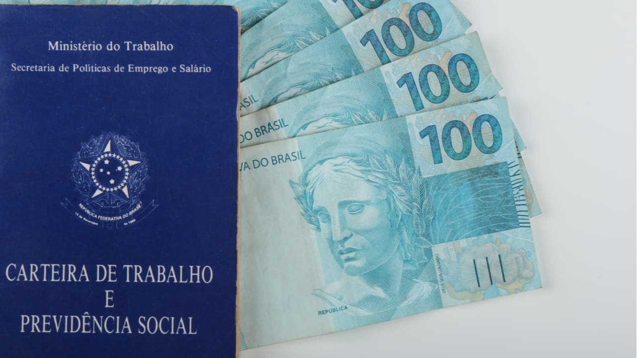 Carteira de Trabalho com notas de 100 reais dentro