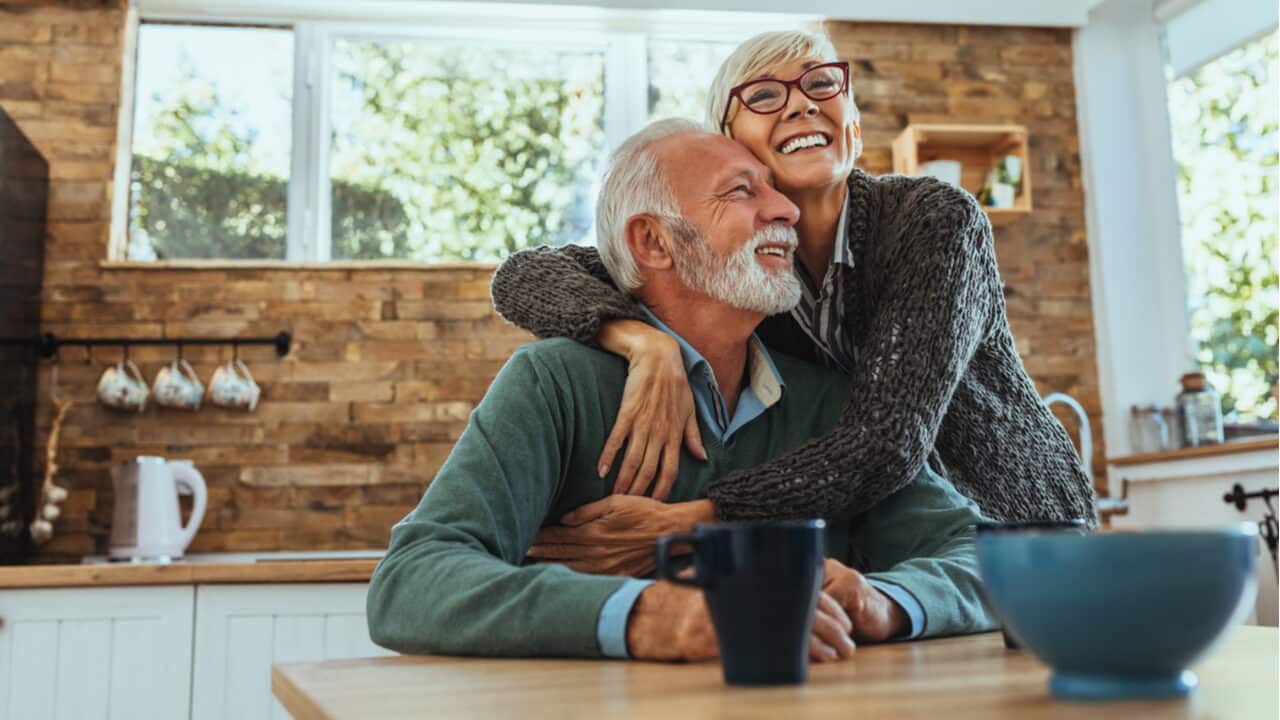 imagem de dois idosos abraçados e sorrindo