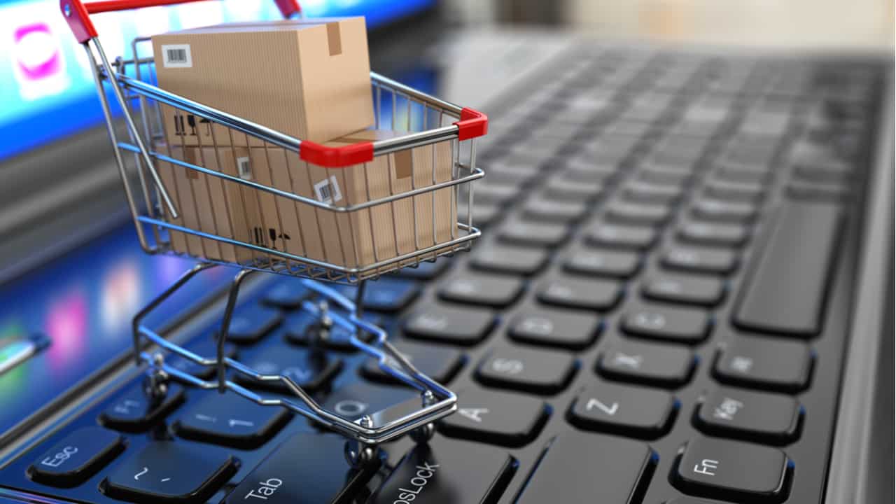 imagem de um teclado de computador com uma miniatura de carrinho de compras