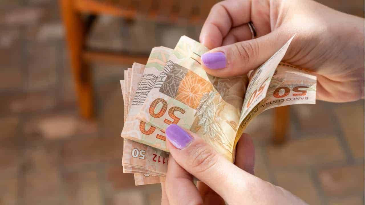 imagem de mulher segurando notas de 50 reais