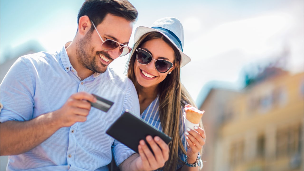 casal de férias com um cartão de crédito e tablet