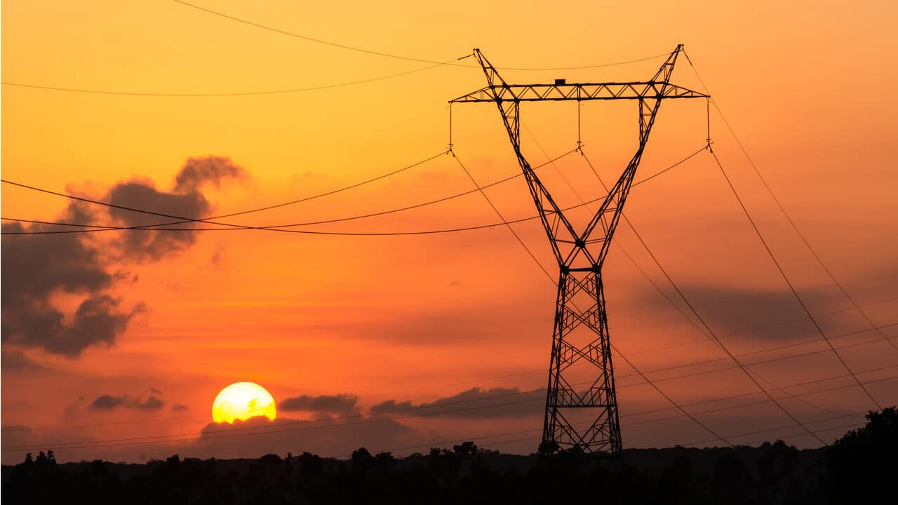 Paisagem com torre de energia e sol se pondo ao fundo