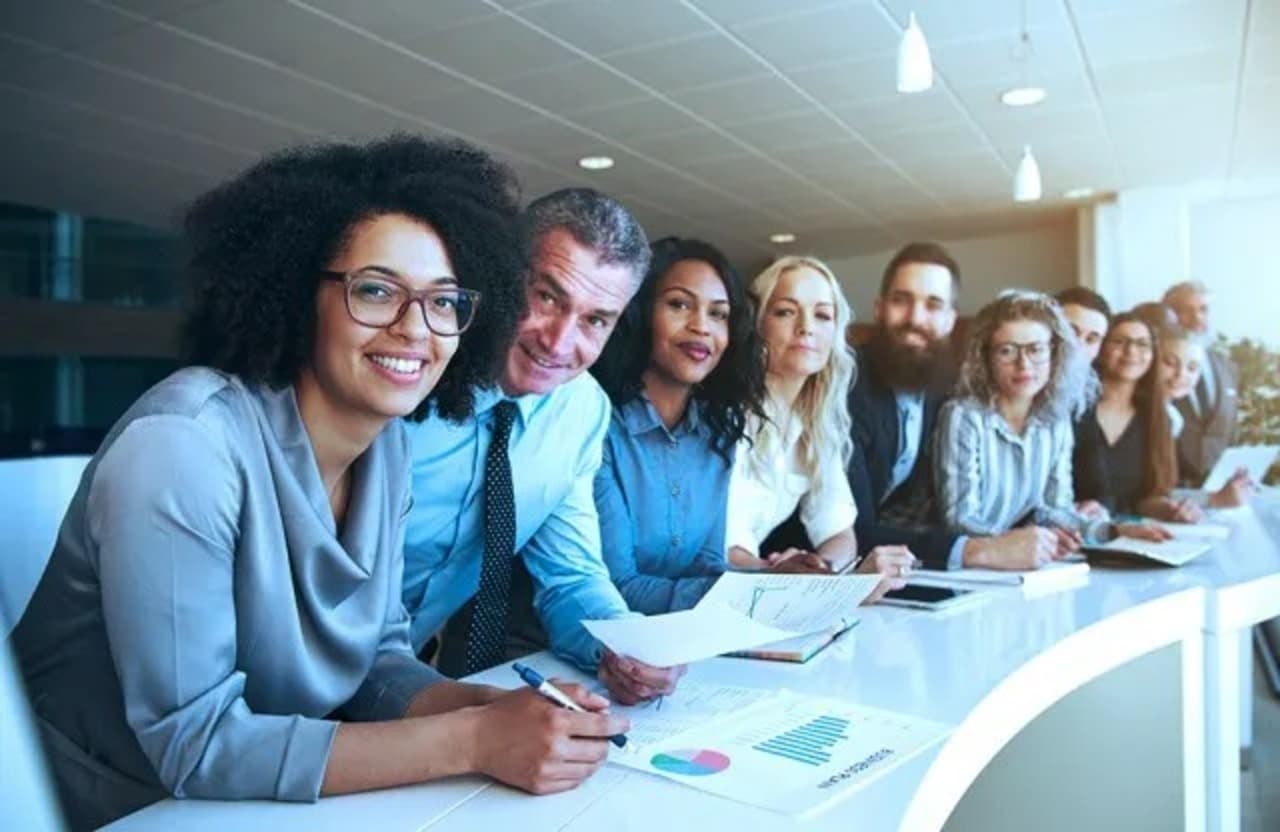 Funcionários da Siemens reunidos em uma mesa sorrindo
