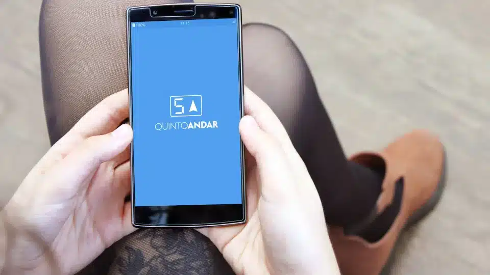 Pessoa utilizando o celular com a imagem do Quinto Andar, plataforma de aluguel de residência