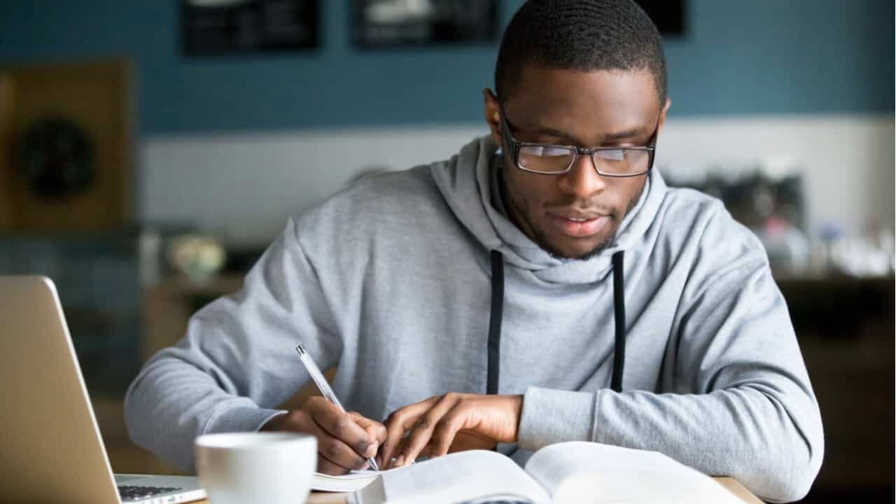 Jovem sentado a mesa estudando