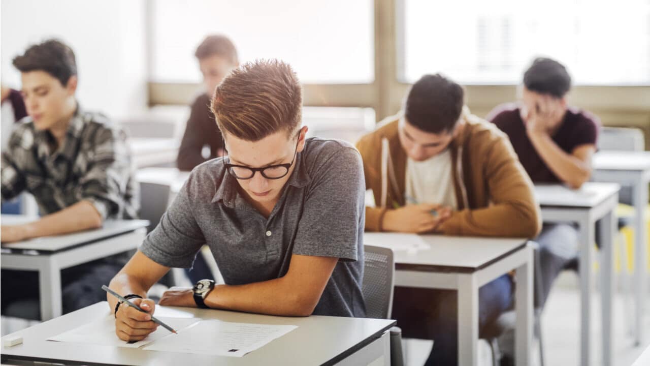 Imagem de estudantes em sala de aula fazendo prova de concurso público