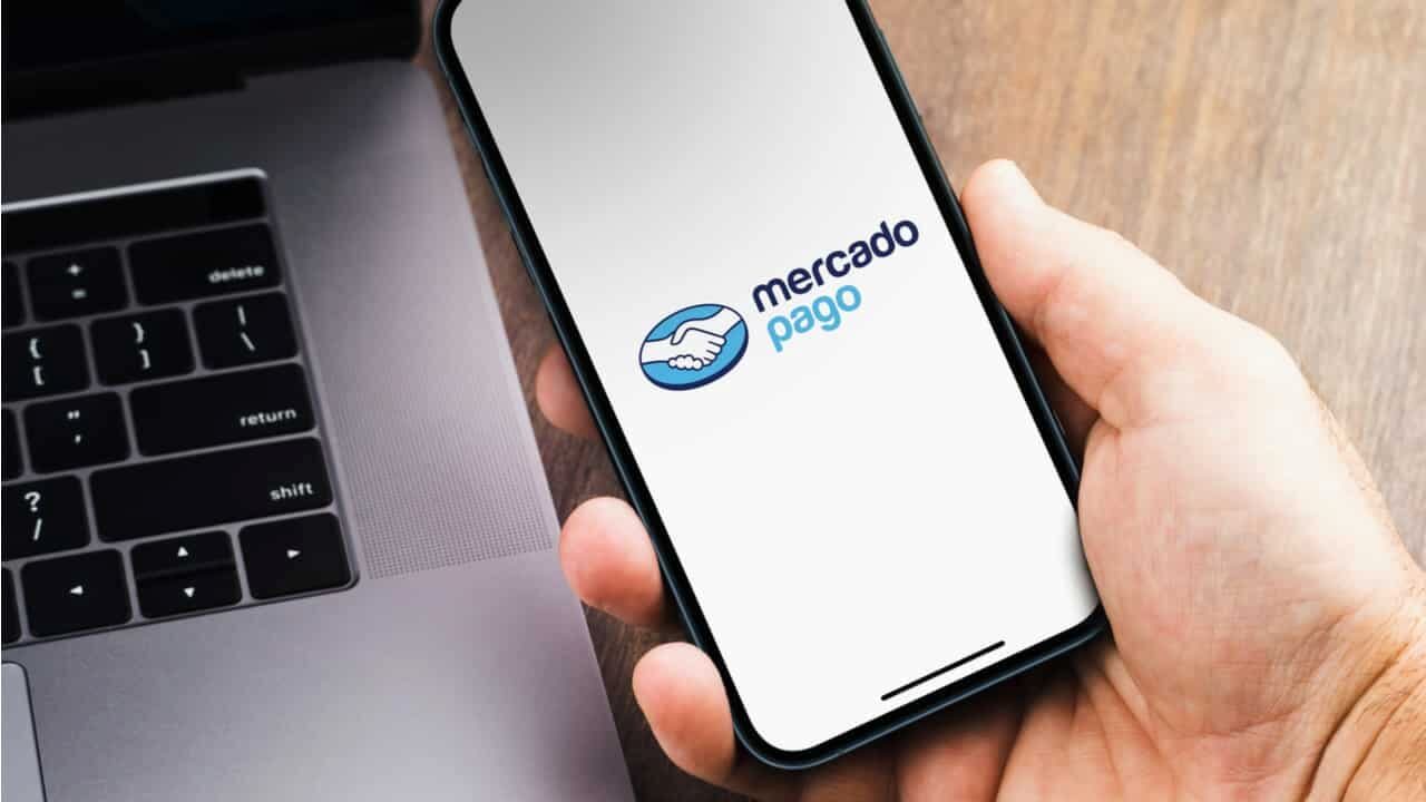 Homem segurando smartphone com aplicativo do Mercado Pago