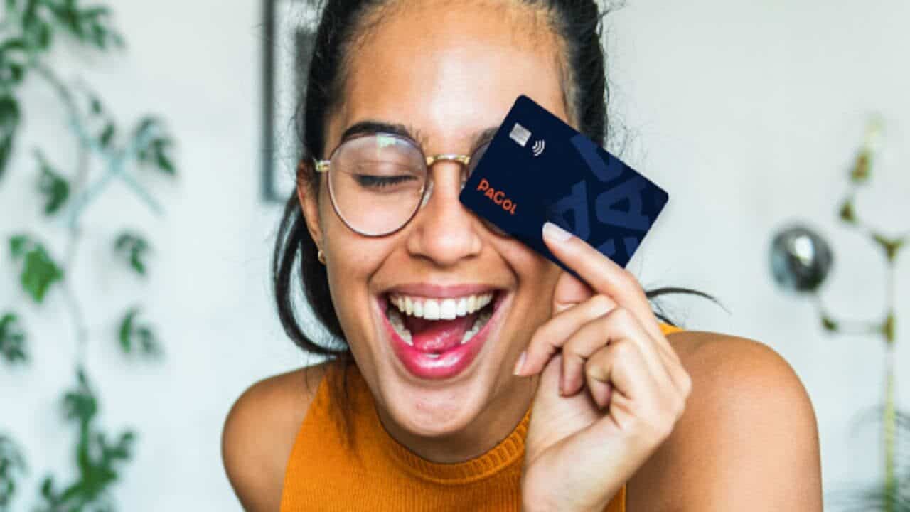 Mulher sorridente segurando seu cartão PaGol