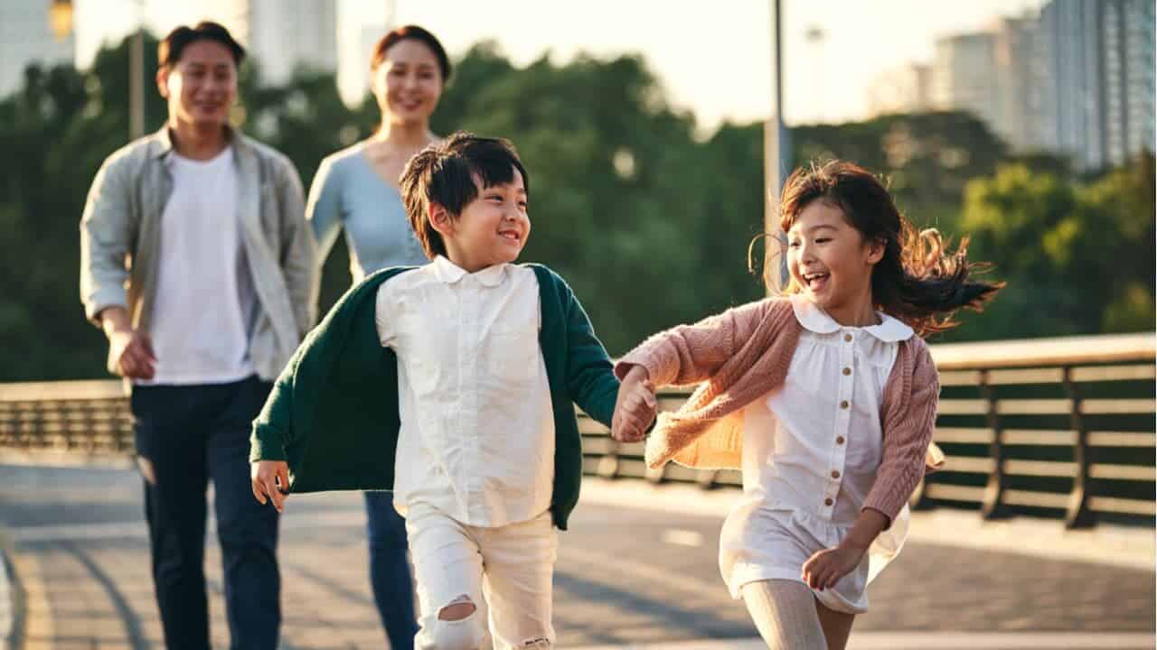 um casal está andando na rua com seus dois filhos em atividade caminhando de mãos dadas, um menino e uma menina.