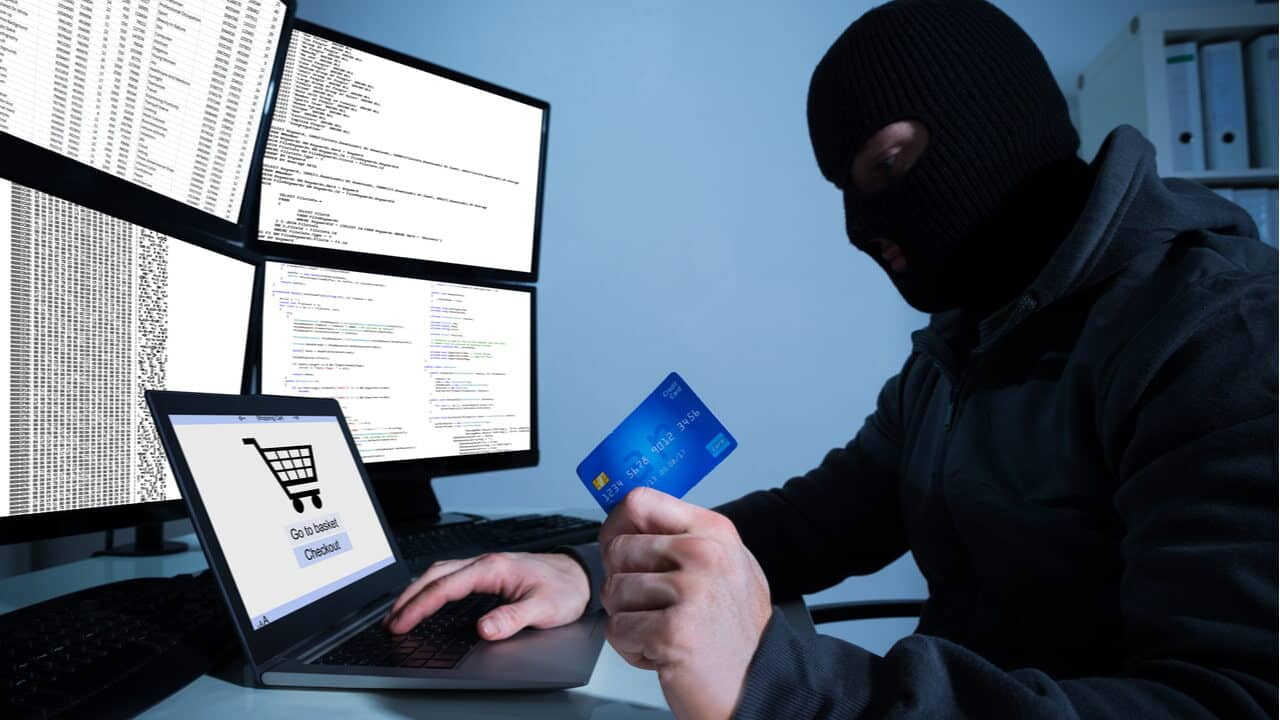 Criminoso encapuzado fazendo compra online com cartão de crédito roubado
