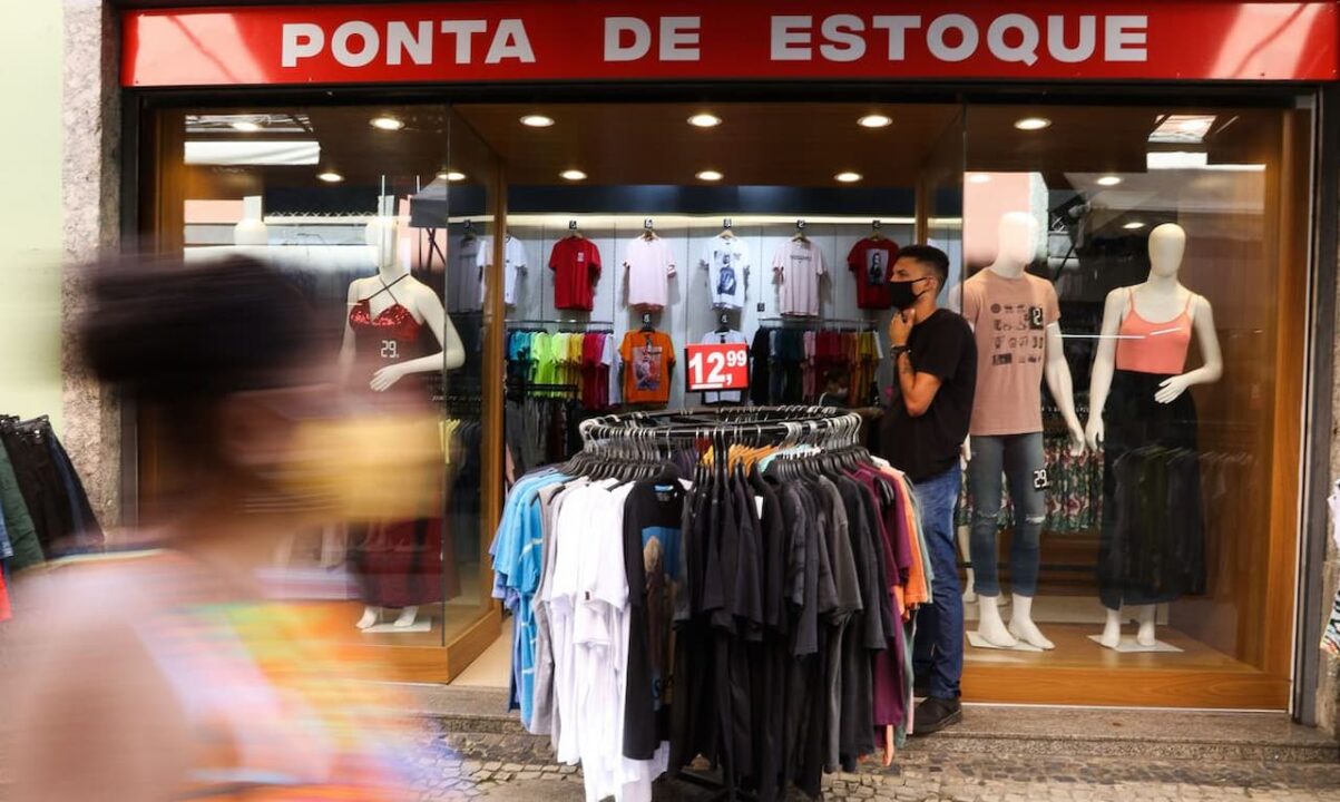 Frente de loja de roupas, com arara de peças de R$ 12,99 na calçada feriados