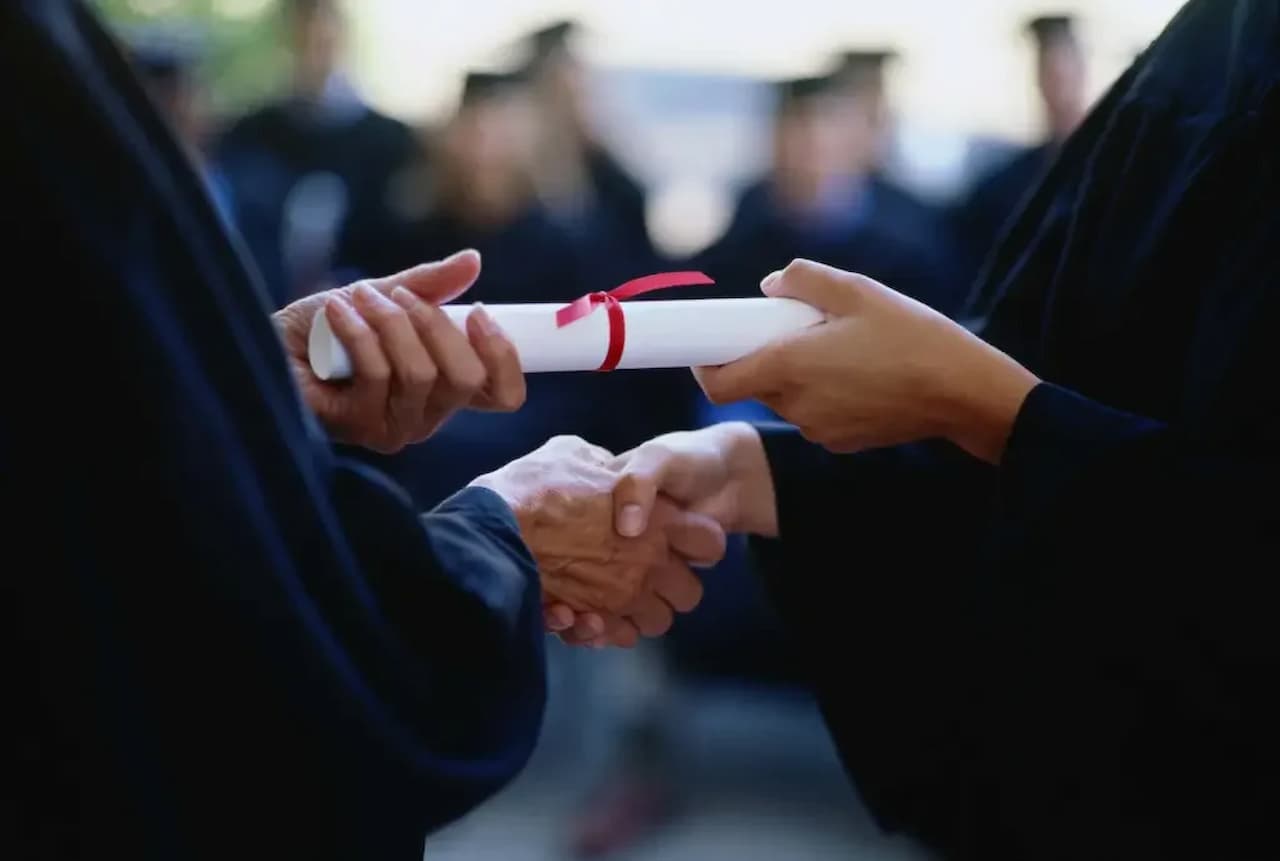 Aluna recebendo seu diploma e cumprimentando seu professor