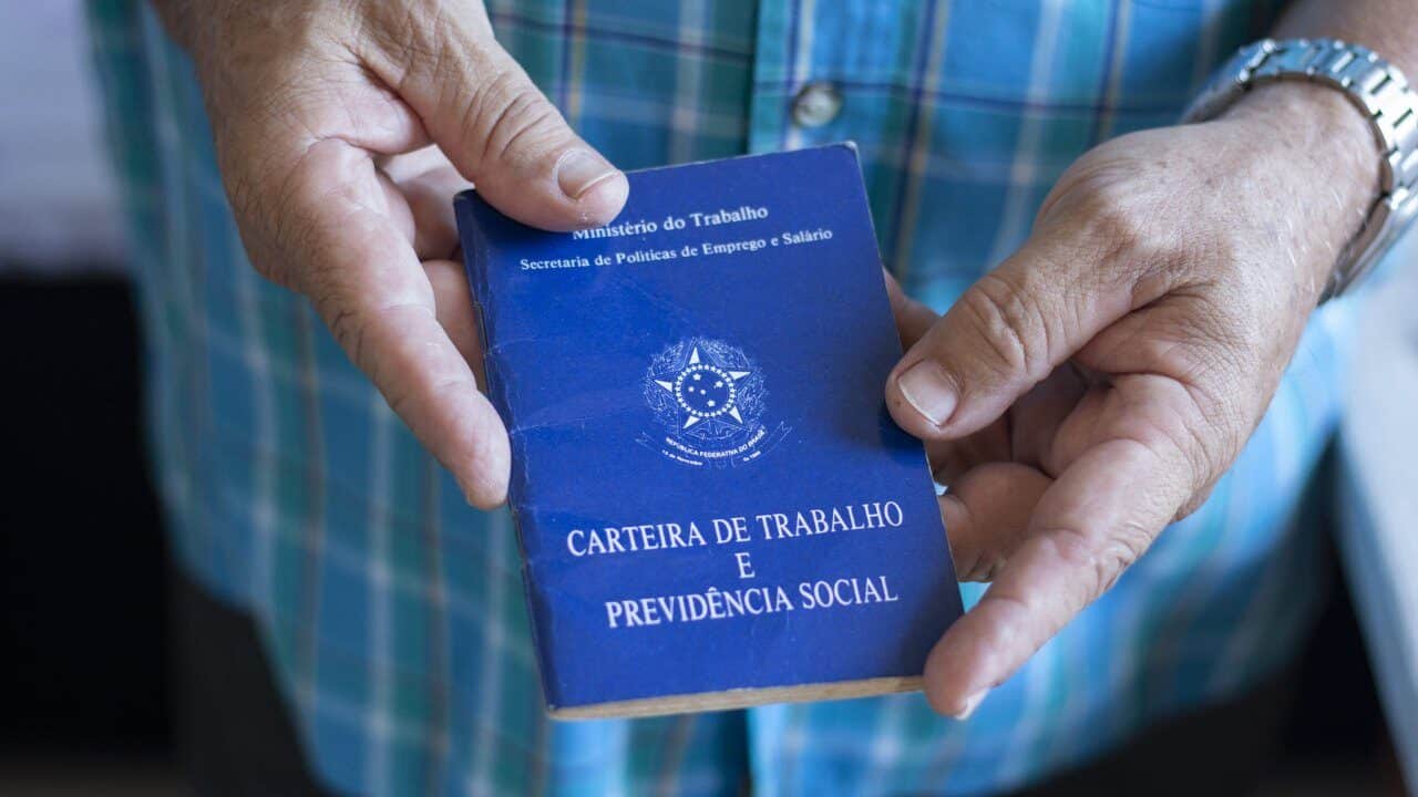 Carteira assinada na mão de senhor