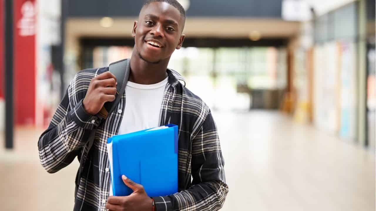 Imagem de um jovem estudante negro carregando seus materiais de estudos