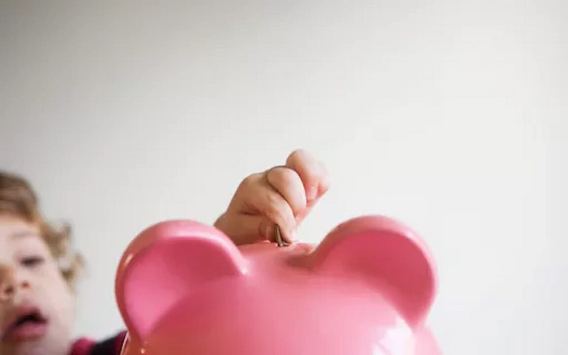Criança colocando moeda no porquinho