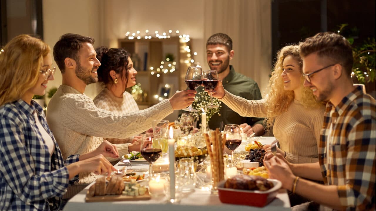 Imagem exibindo celebração de fim de ano. Amigos reunidos numa mesa de jantar