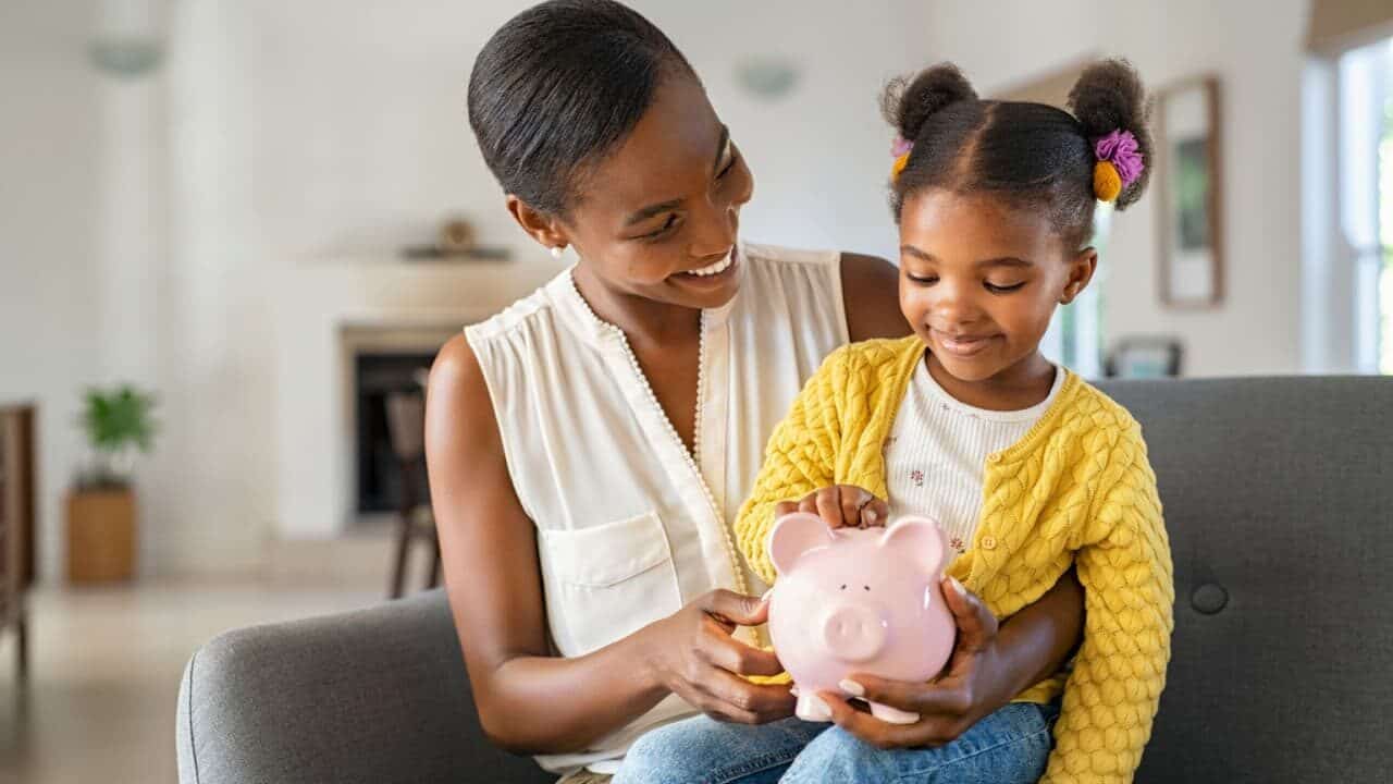 Mãe e filha juntas com um cofrinho de moedas no colo