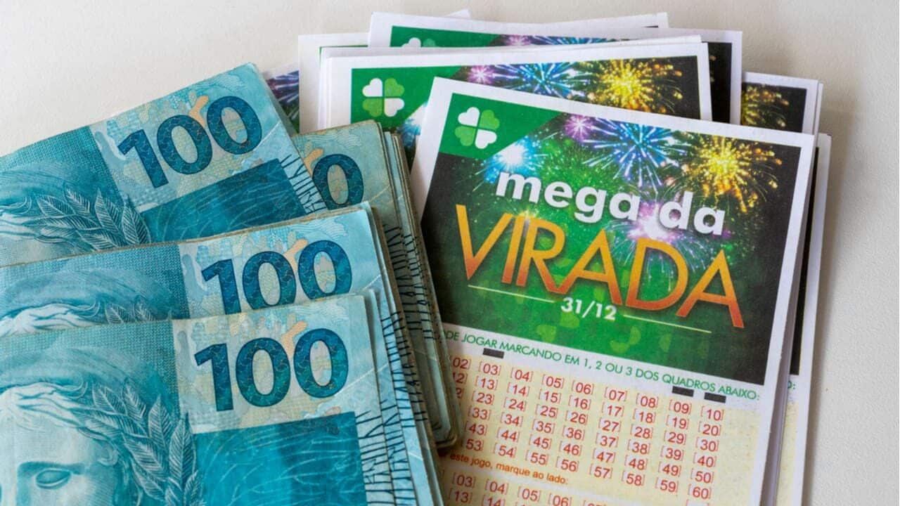 Cartões de aposta na Mega da Virada ao lado de várias notas de 100 reais