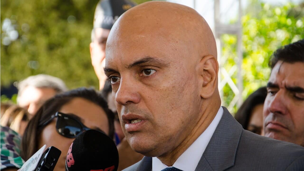 Ministro Alexandre de Moraes em entrevista coletiva rodeado por microfones de emissoras