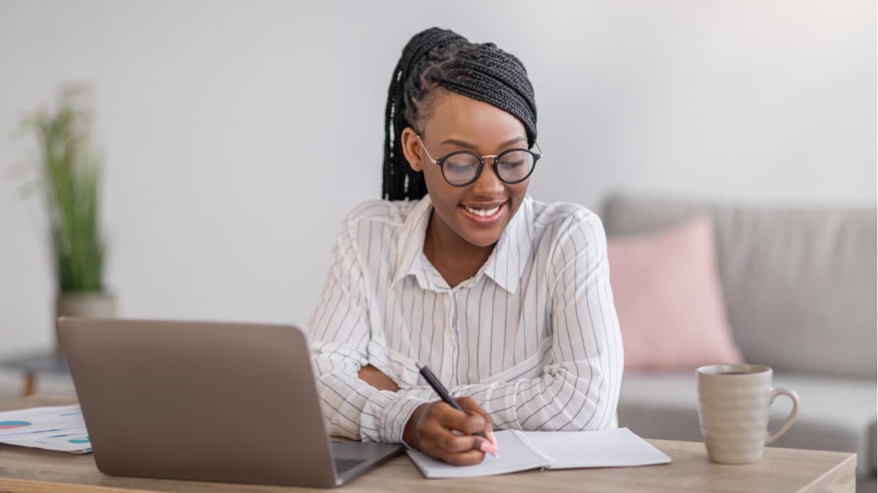 mulher estudando com cursos gratuitos pelo computador enquanto sorri