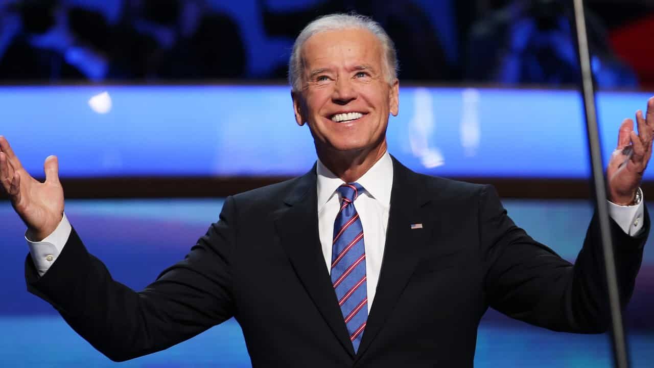 Presidente dos EUA, Joe Biden, sorrindo com as mãos para cima