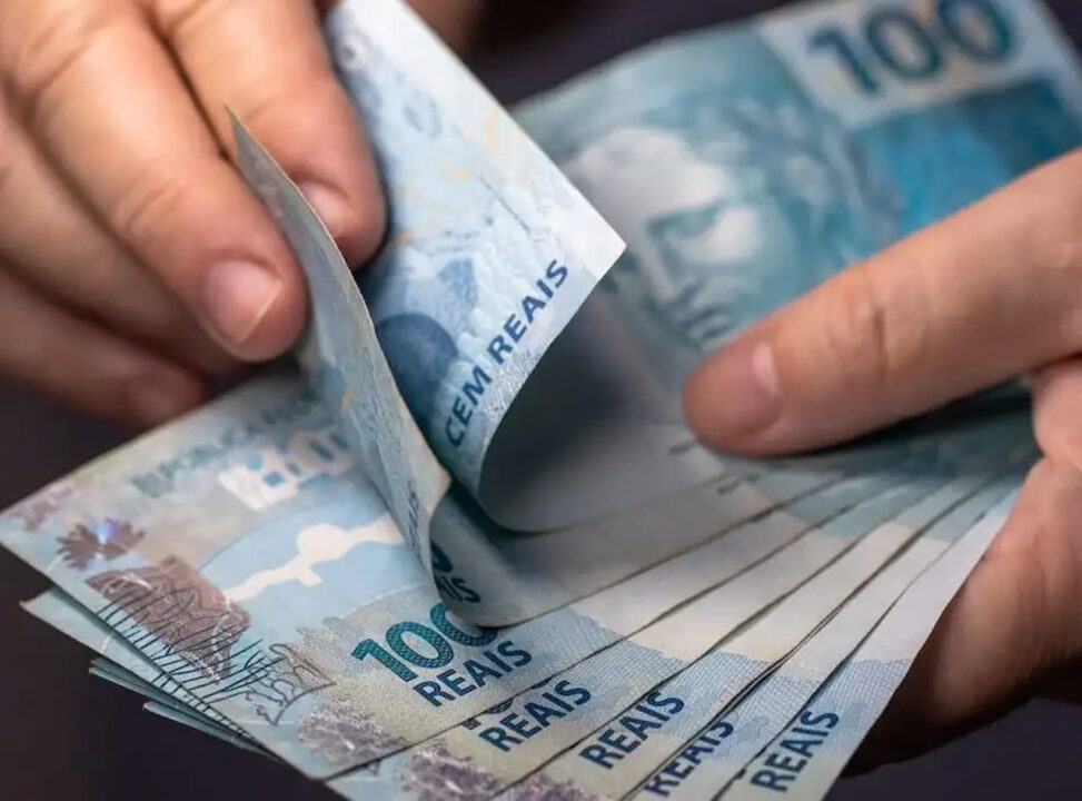 Mão com leque de notas de cem