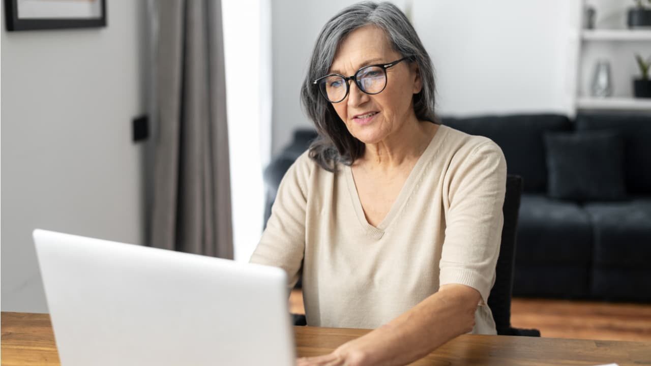 Senhora utilizando um computador, simbolizando a aposentadoria que pode sofrer cortes do INSS.