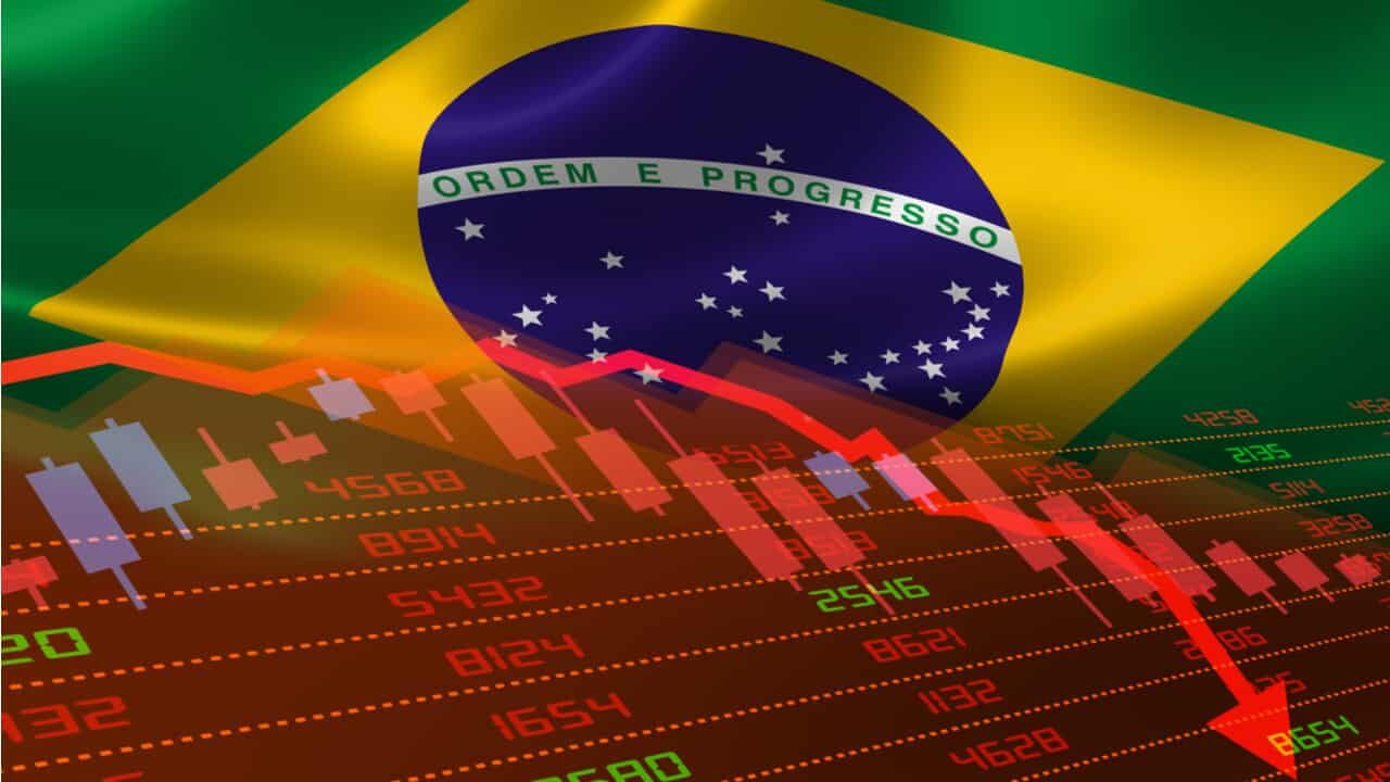 Imagem de gráficos apontando queda com bandeira do Brasil atrás
