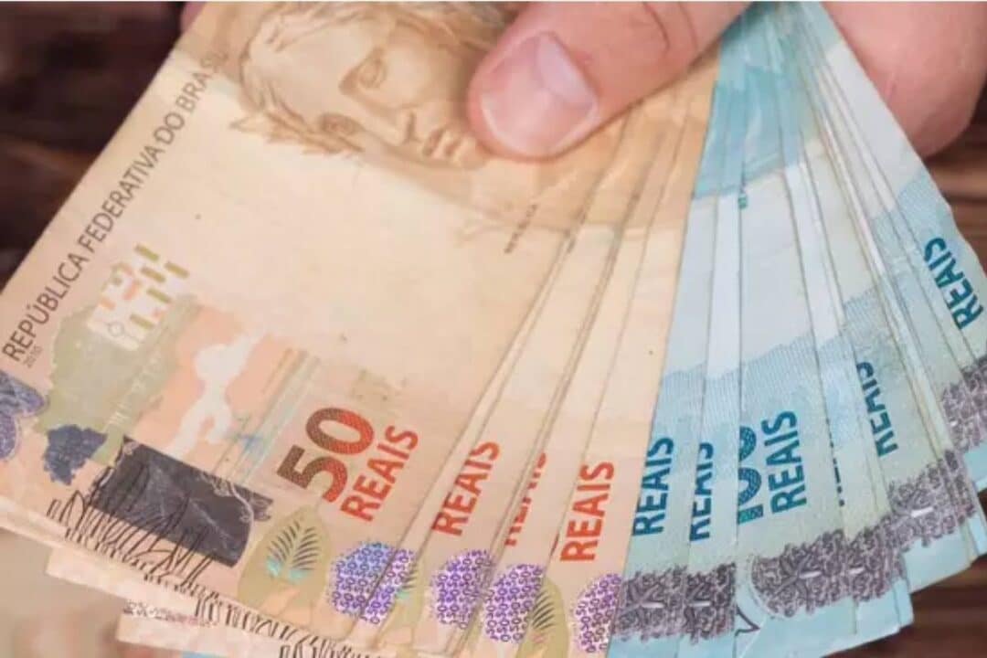 Várias notas de 100 e 50 reais na mão de uma pessoa