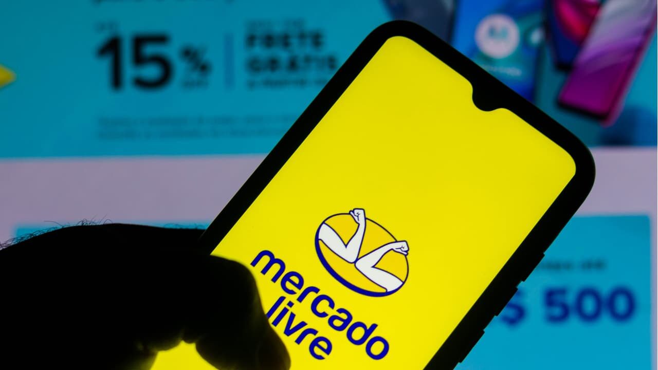 Mão segurando celular com a logo do Mercado Livre na tela