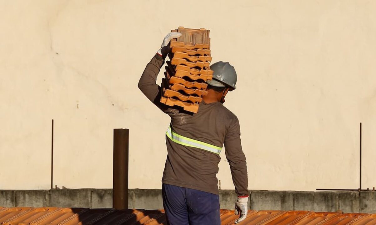 pedreiro carregando materiais de construção no ombro