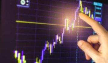 Mão apontando para gráfico que mostra oscilações do mercado