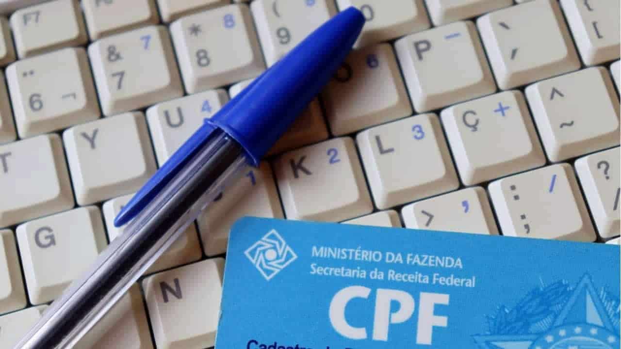 CPF e uma caneta azul sobrepostos em um teclado branco