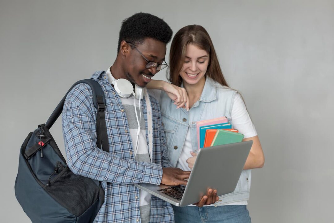 estudantes sendo um garoto com mochila e notebook enquanto mostra a tela para uma garota que segura cadernos