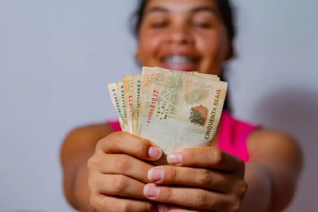 mulher segurando dinheiro para representar o auxílio para mães solteiras