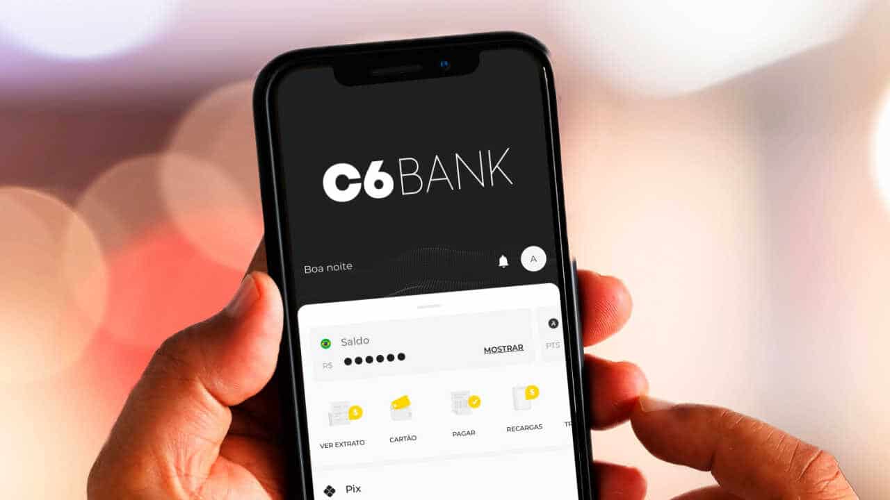 Celular na mão com app do C6 Bank aberto na tela inicial