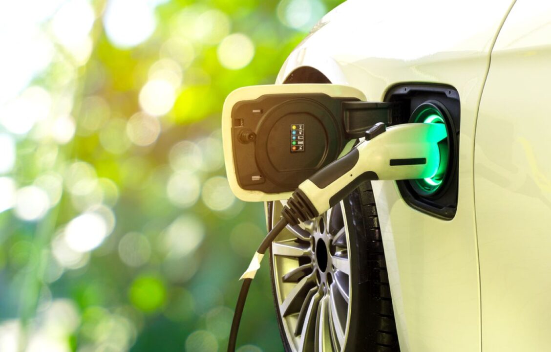 Carro elétrico branco sendo recarregado em um eletroposto