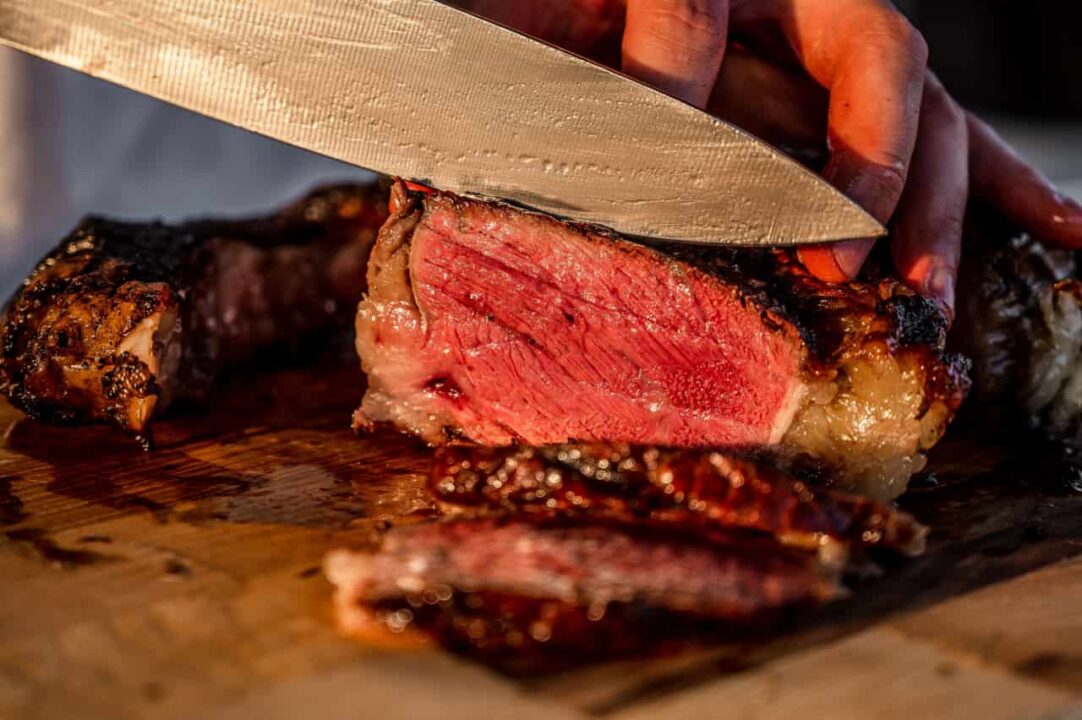 Peça de carne sendo fatiado em uma tábua