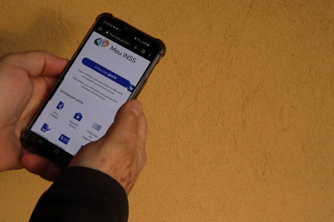 Pessoa mais velha segurando um celular com o aplicativo Meu INSS aberto