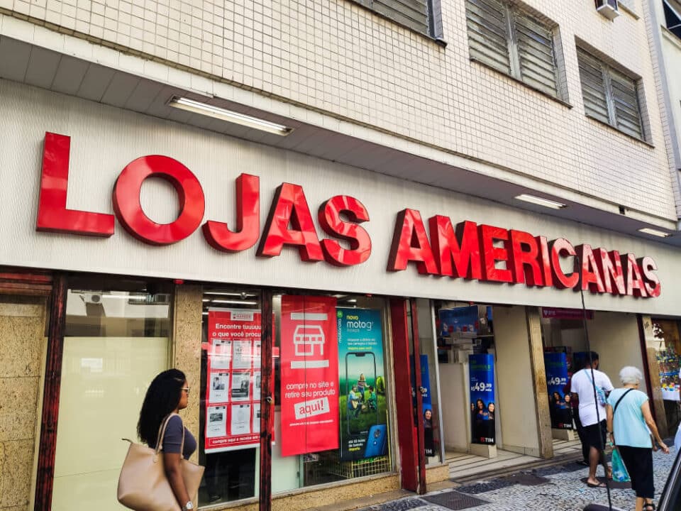 Fachada da loja americanas com pessoas passando.