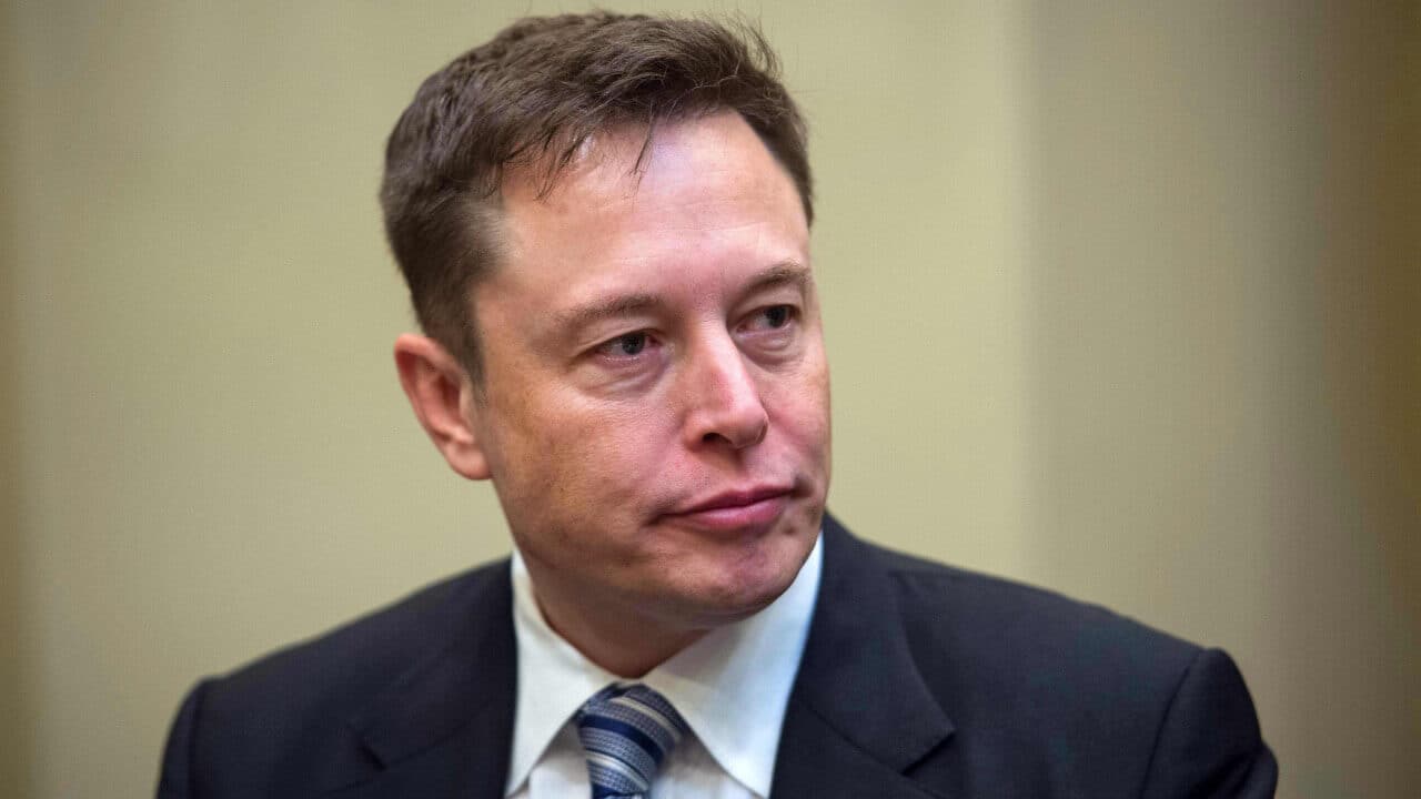 Empresário Elon Musk de terno com expressão séria