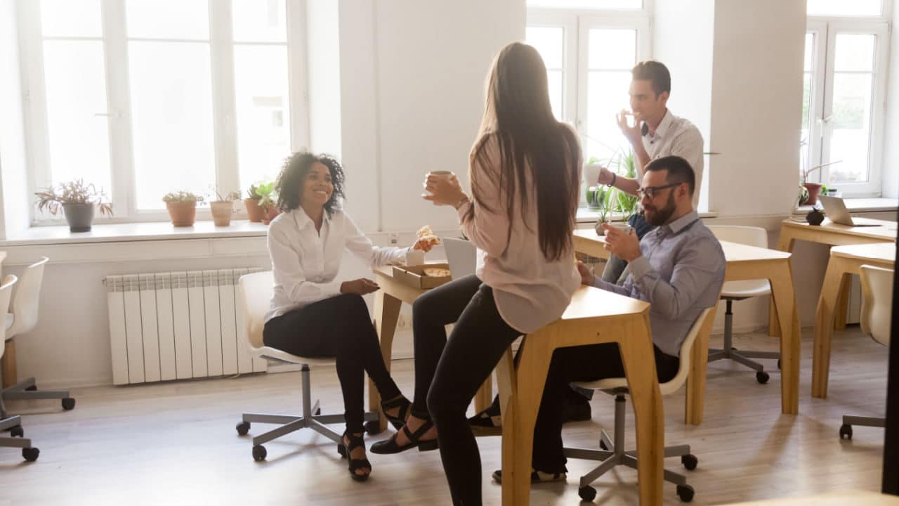 grupo de pessoas durante o intervalo no trabalho conversando ao redor de uma mesa
