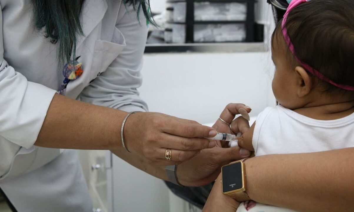 Covid-19- Enfermeira aplicando vacina em bebê de colo